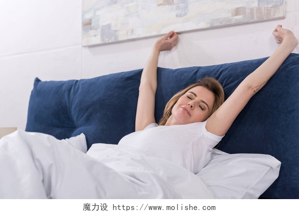 一个女人在床上睡醒伸懒腰床上睡后女性伸展的画像